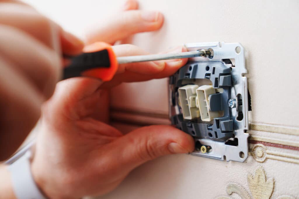 close up of electrician hands installing a light switch