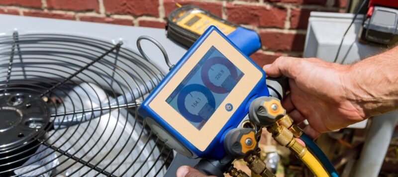 closeup of a pressure reading being held by an hvac technician to perform maintenance on an outdoor unit