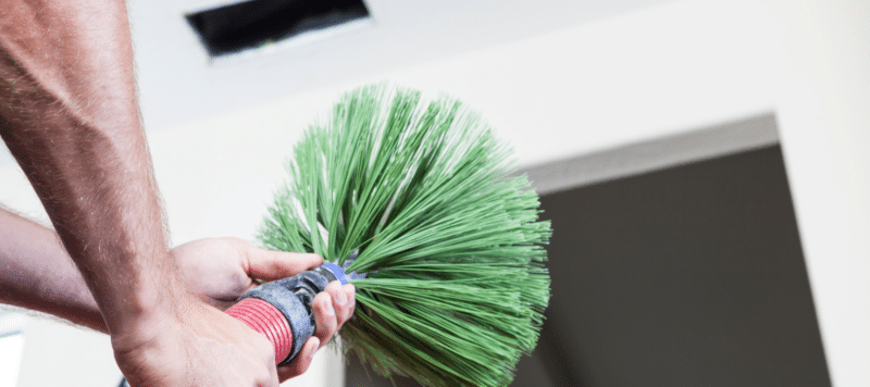 Technician holding a brush tool for air duct cleaning